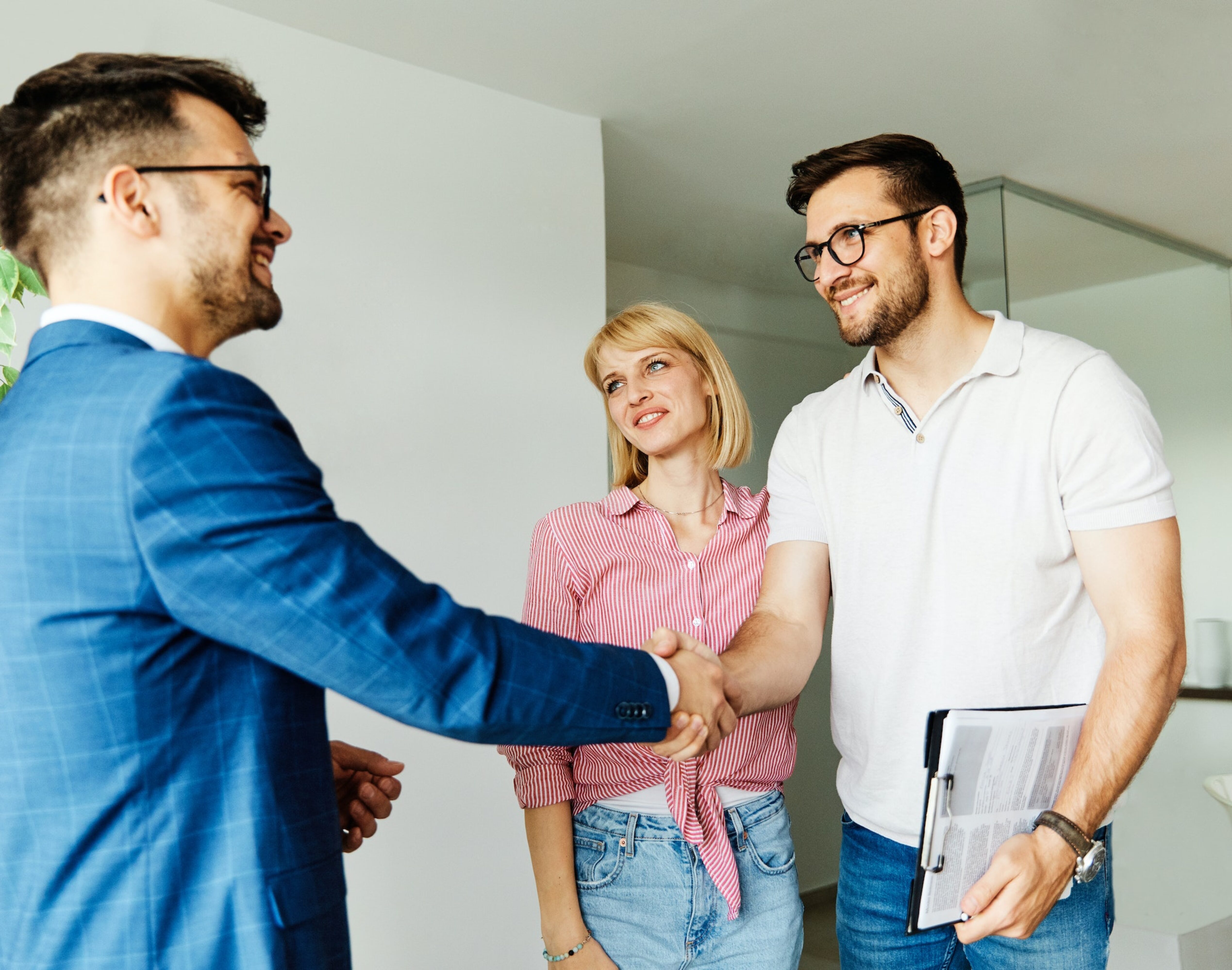 Real estate agent opening a gate to a happy couple that came to an open house