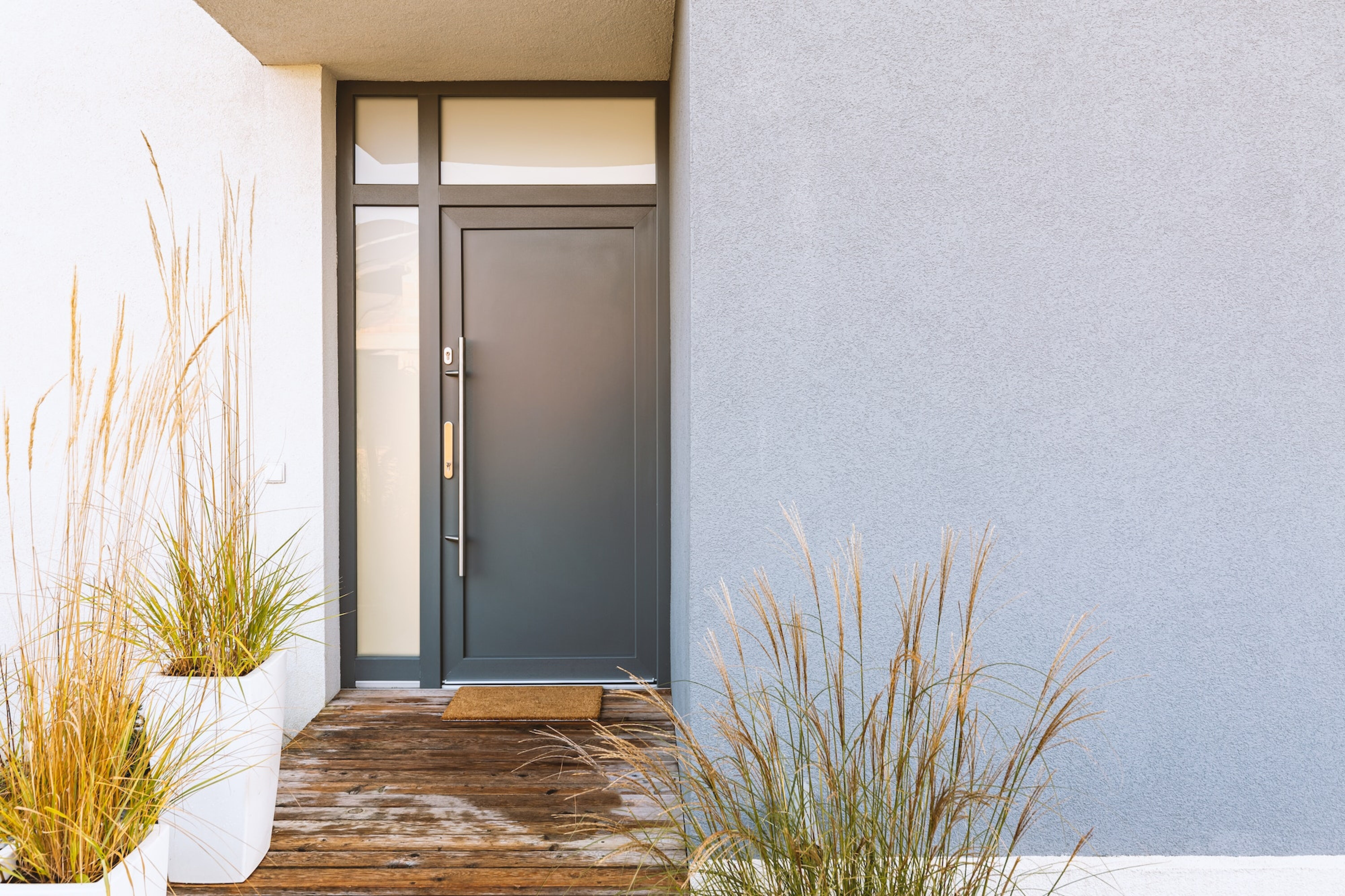 Grass in pot and wooden path in front of front door stylish suburban house