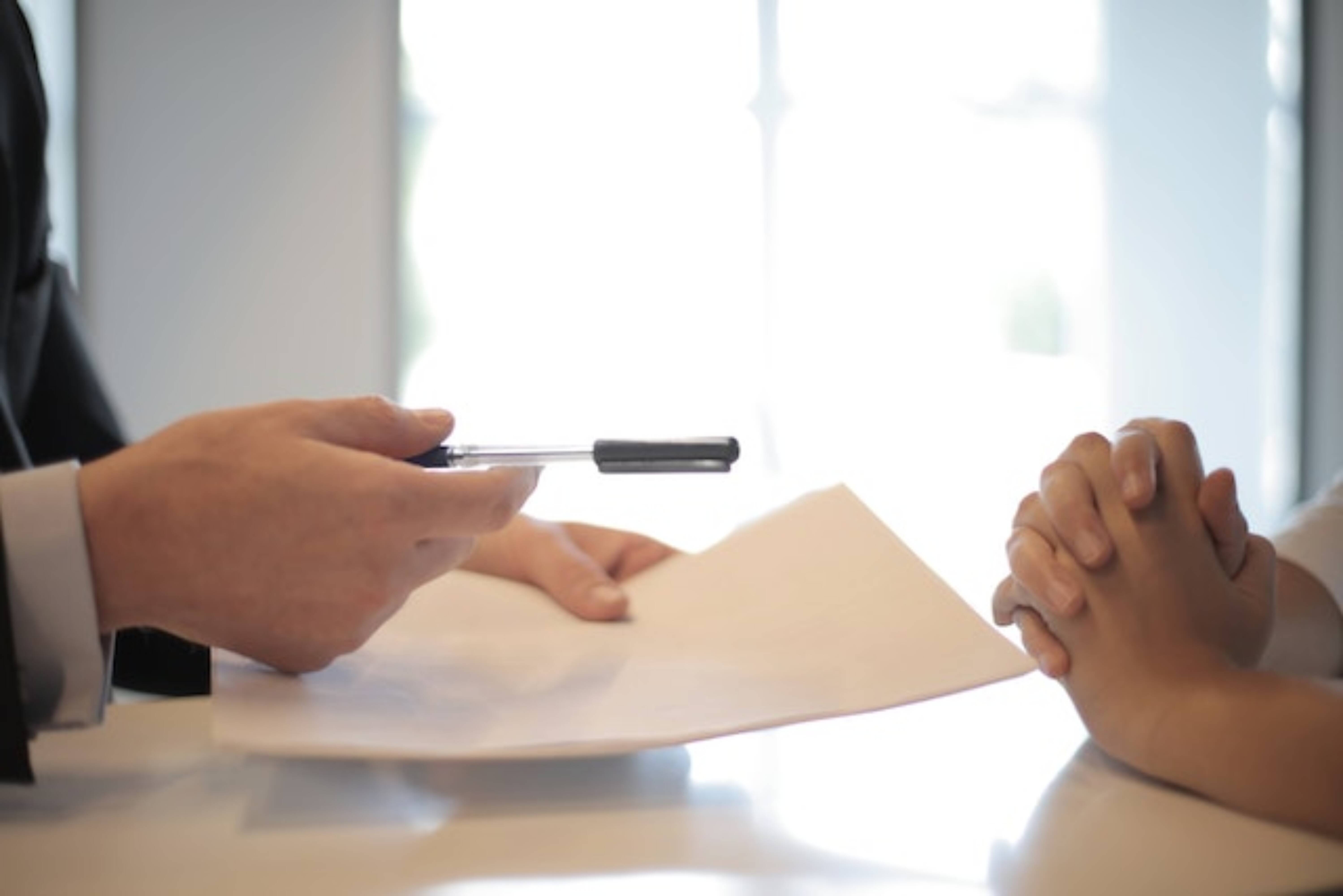 A person handing a document for signing to another person.