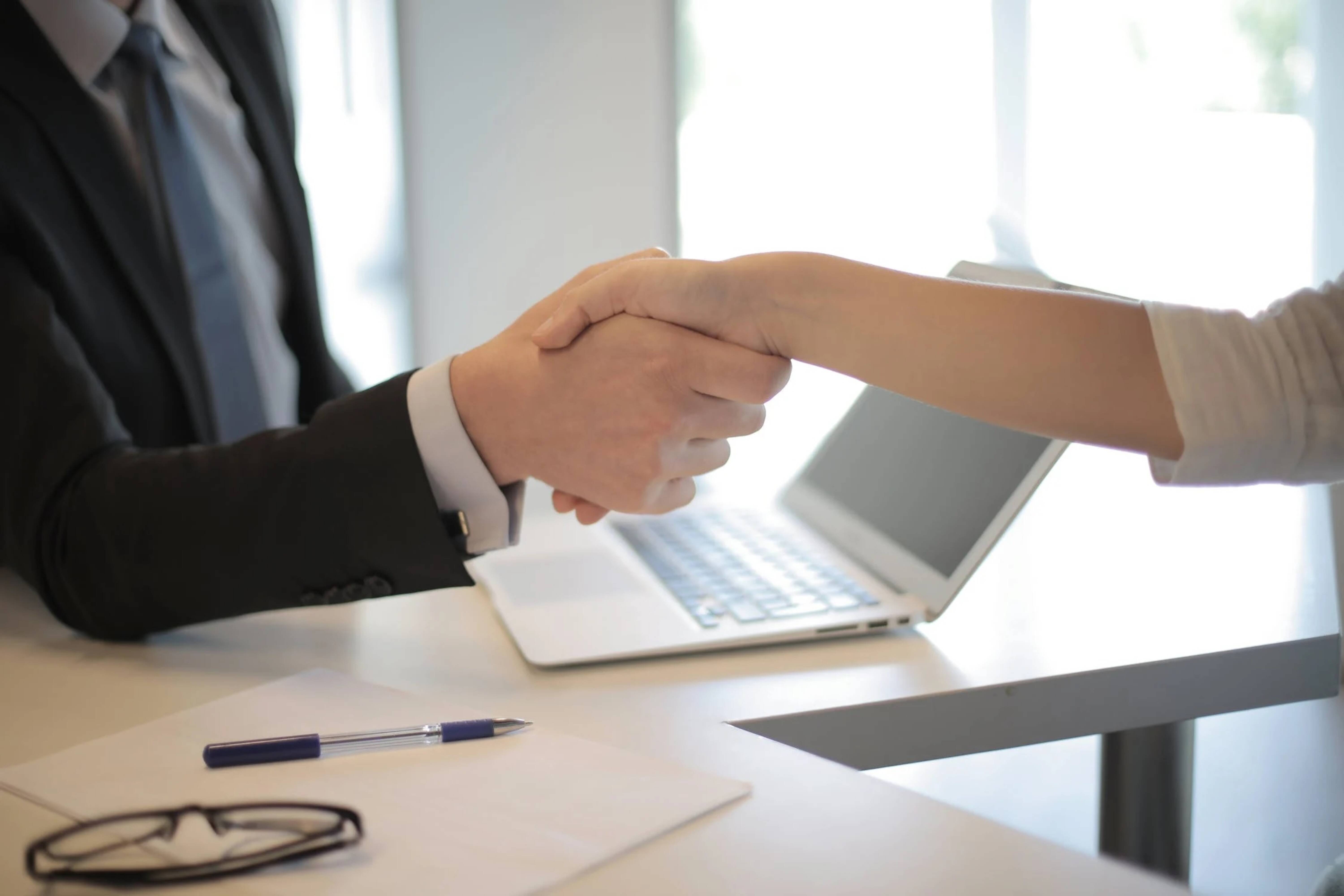 A close-up of two people shaking hands in an office.