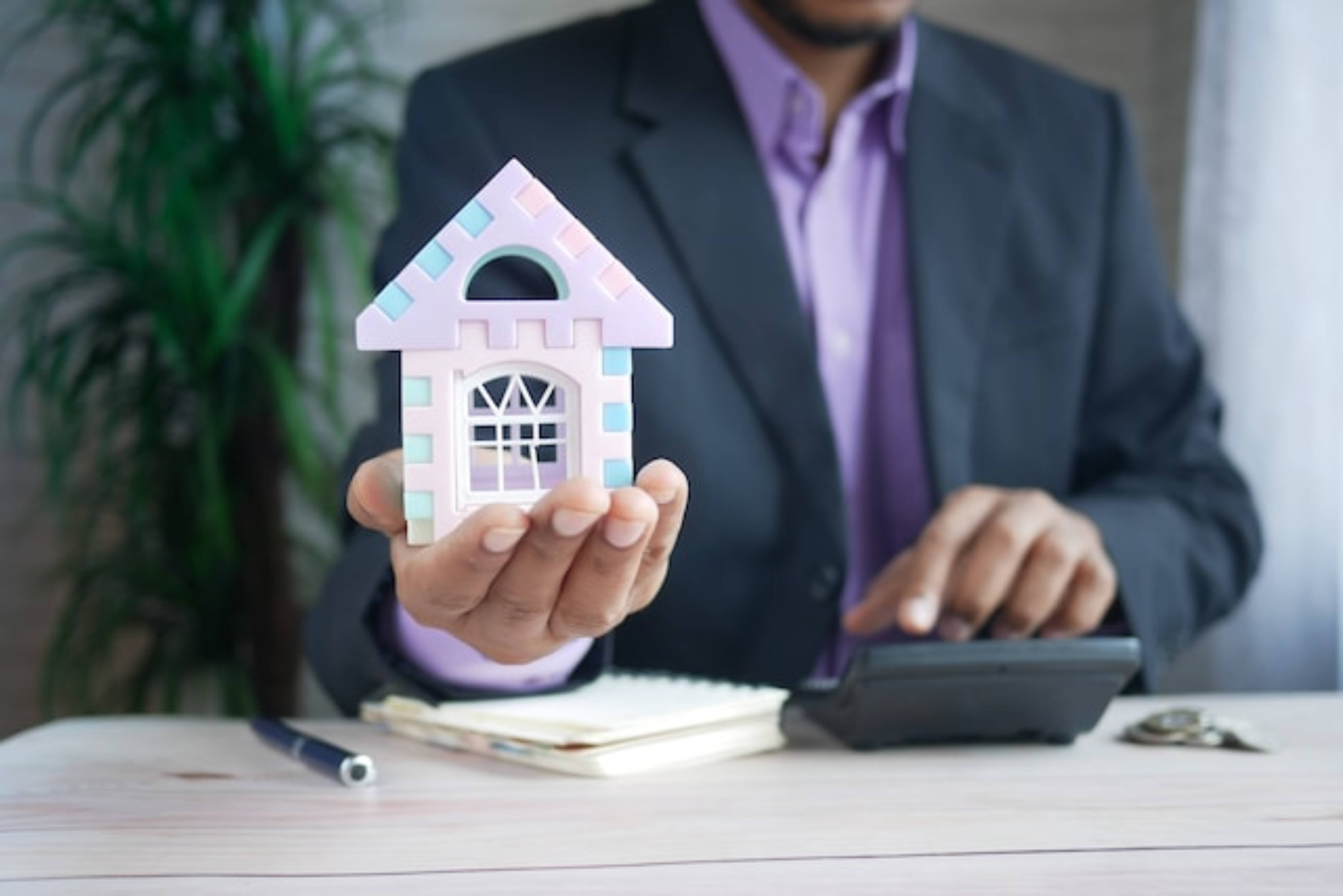 Property manager holding a small purple model of a house